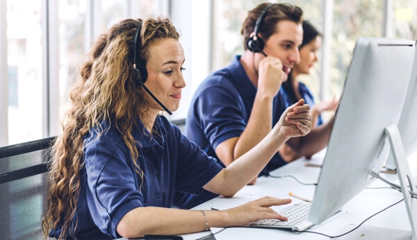 three employees on the phone and computer talking with customers