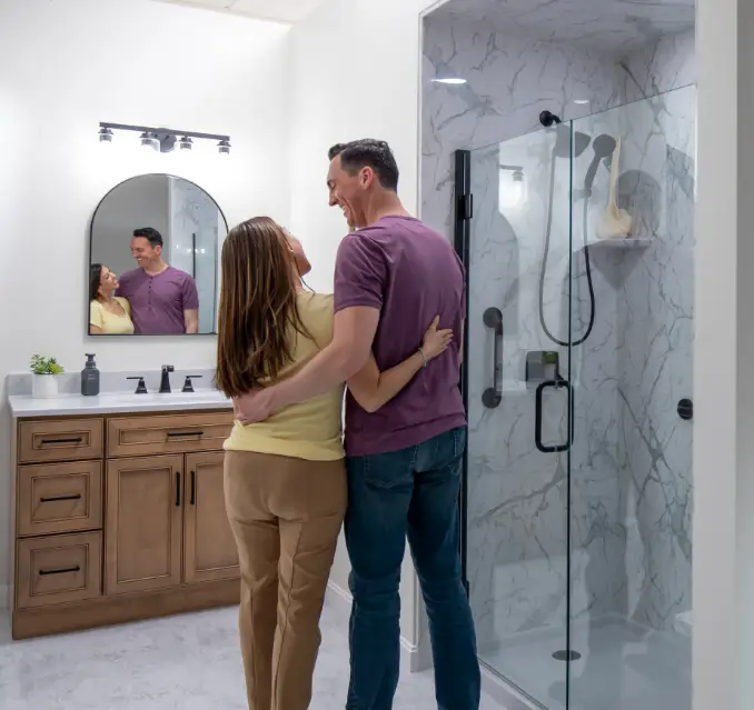 happy couple looking at their recently completed bathroom remodel with shower install and glass doors
