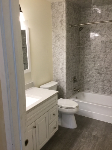 recently remodeled bathroom with new flooring tub shower fixtures toilet lighting and vanity