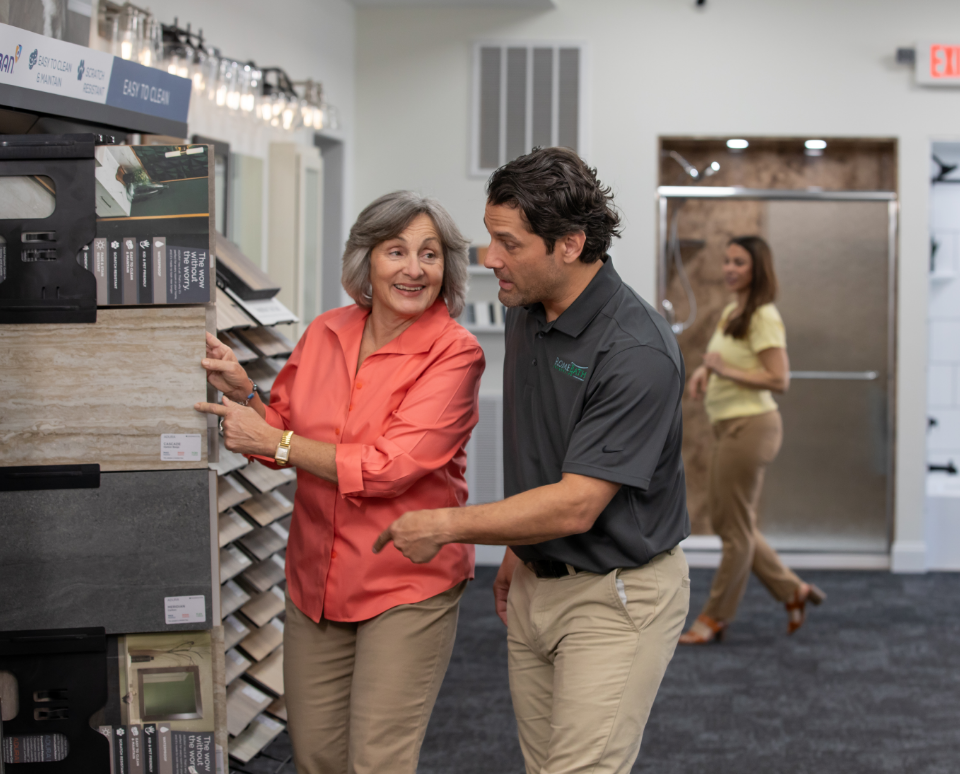 Rome Bath Remodeling employee helps customer in the showroom pick out flooring for her bathroom