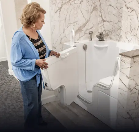 woman exploring the advantages of walk-in tubs such as the outward facing door, grab bars and supported seat